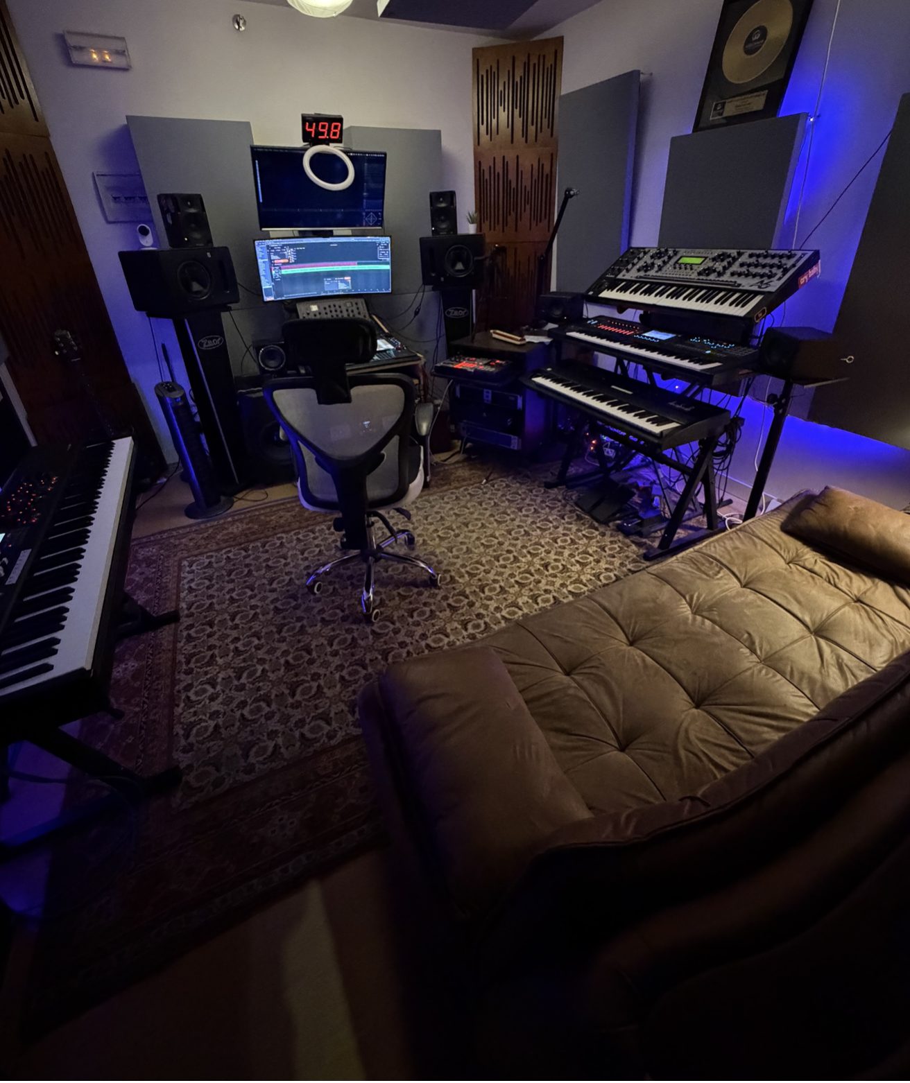 Control room con monitores, pantallas, teclados y sofá